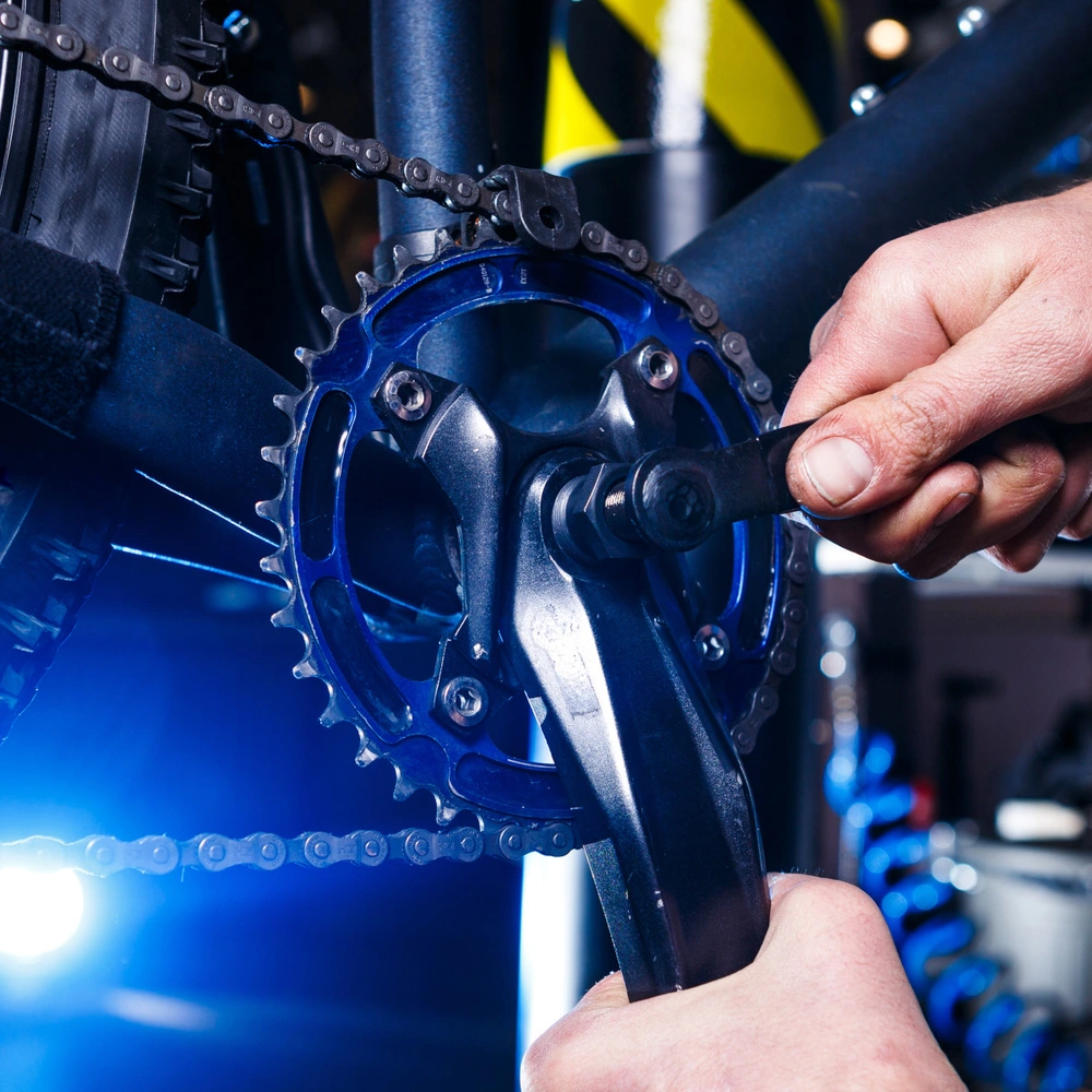 DIY Fahrradkurbel wechseln mit Tipps von linexo Männerhände schrauben an der Fahrradkurbel in einer Werkstatt