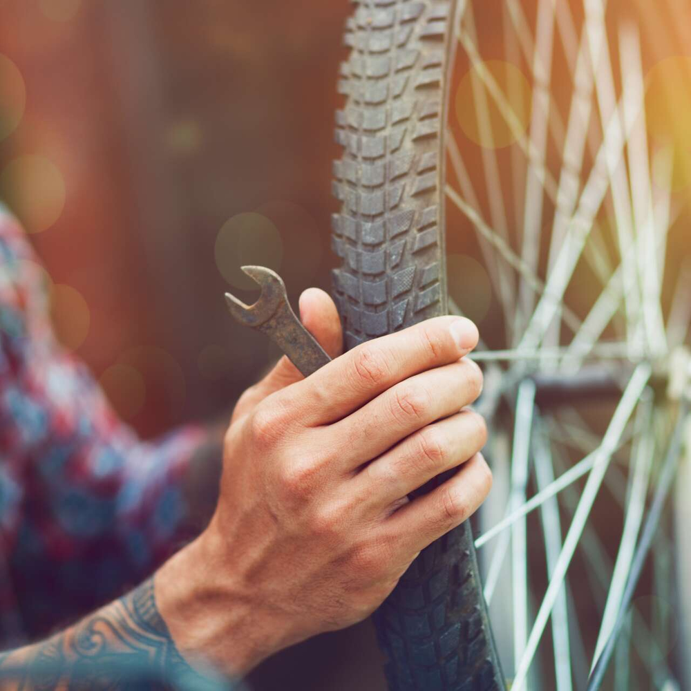 Ein Fahrradreifen-Wechsel kann mit etwas Übung leicht selbst durchgeführt werden. Ein Mann repariert sein Fahrrad.