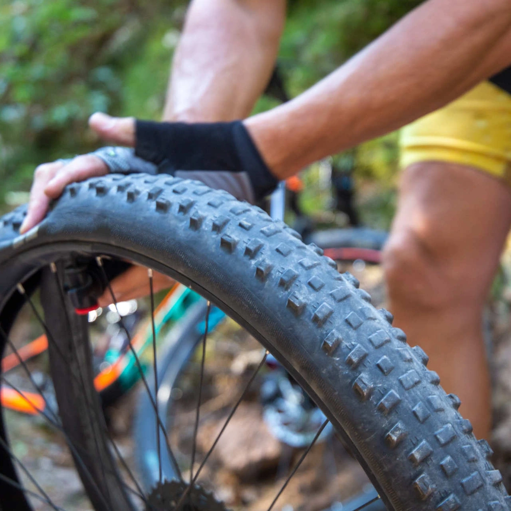 Fahrradschlauch flicken – so geht's Mann prüft Druck von Fahrradschlauch mit Händen