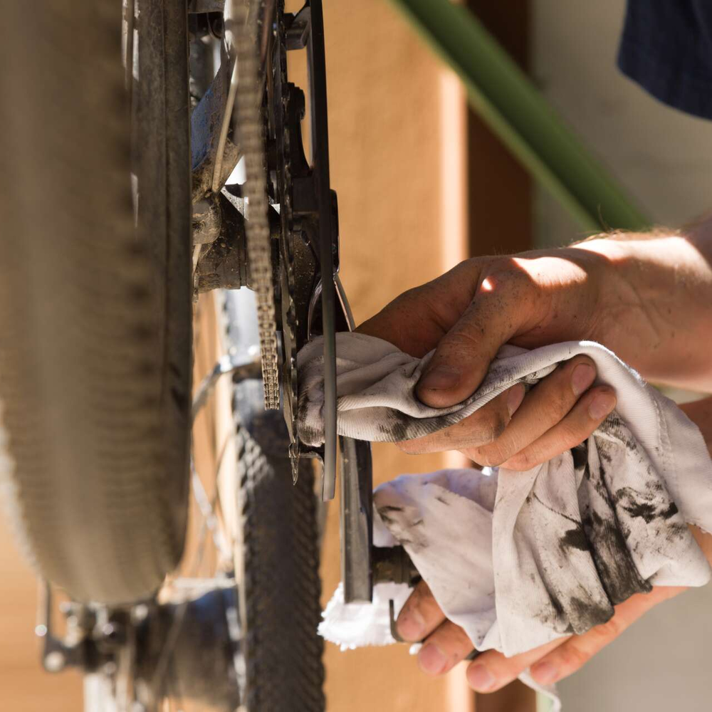 Ein regelmäßiger Fahrradcheck ist sinnvoll, um die Sicherheit im Straßenverkehr zu gewährleisten. Schaltung eines Fahrrads wird mit einem Lappen gereinigt.