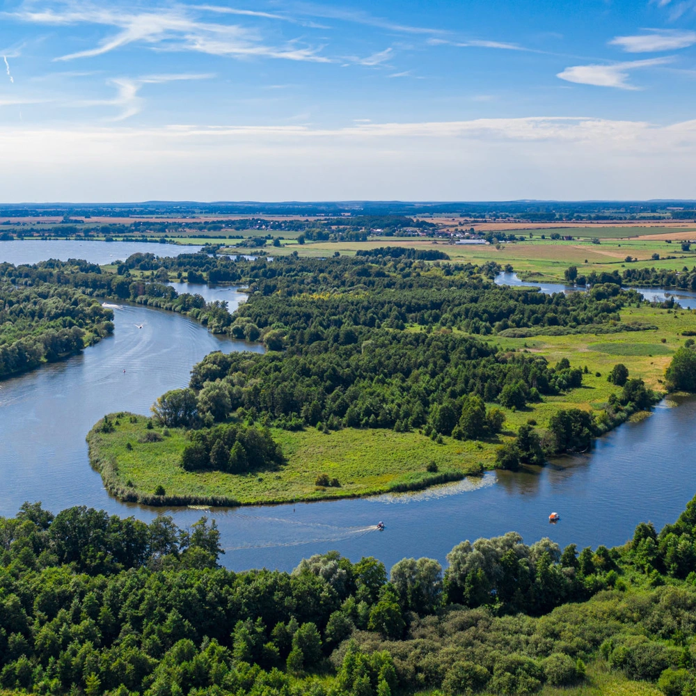 Entdecke den Havel-Radweg Luftaufnahme eines weitläufigen, grünen Flusslandschaft mit klaren blauen Himmel.
