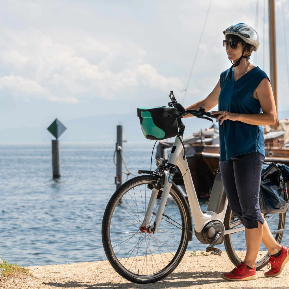 Das Lemmo One gewann den Design & Innovation Award 2023. Frau mit Helm steht neben Fahrrad an einem See.