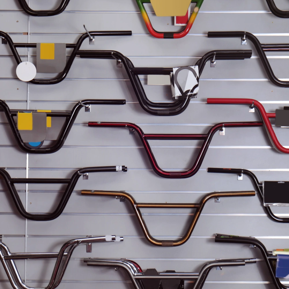 Eine Wand mit verschiedenen Fahrradlenkern in unterschiedlichen Farben und Designs.