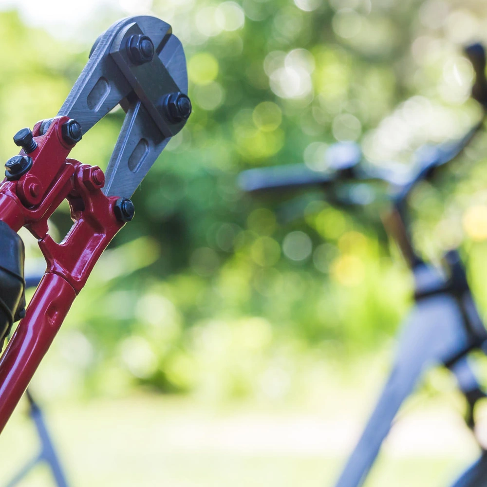 Schütze jetzt dein Fahrrad vor Diebstählen. Bolzenschneider wird vor Fahrrad gehalten.