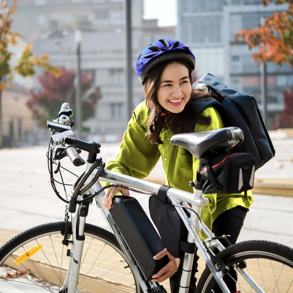 Radfahrerin setzt einen Akku in ihr E-Bike ein bei herbstlichen Ambiente