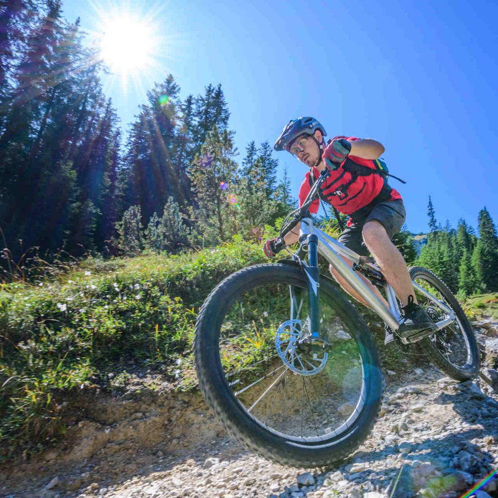 MTB Fahrtechnik – diese Tipps und Tricks helfen Mann fährt auf dem Mountainbike durch die Berge