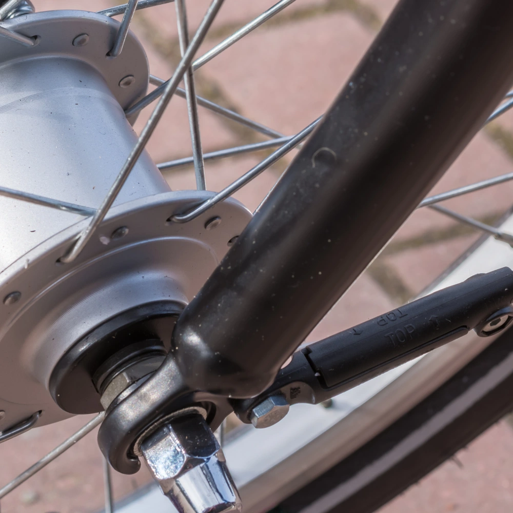 Nahaufnahme des Fahrradnaben mit Speichen, Achse und Nabendynamo auf einem Pflastersteinboden.