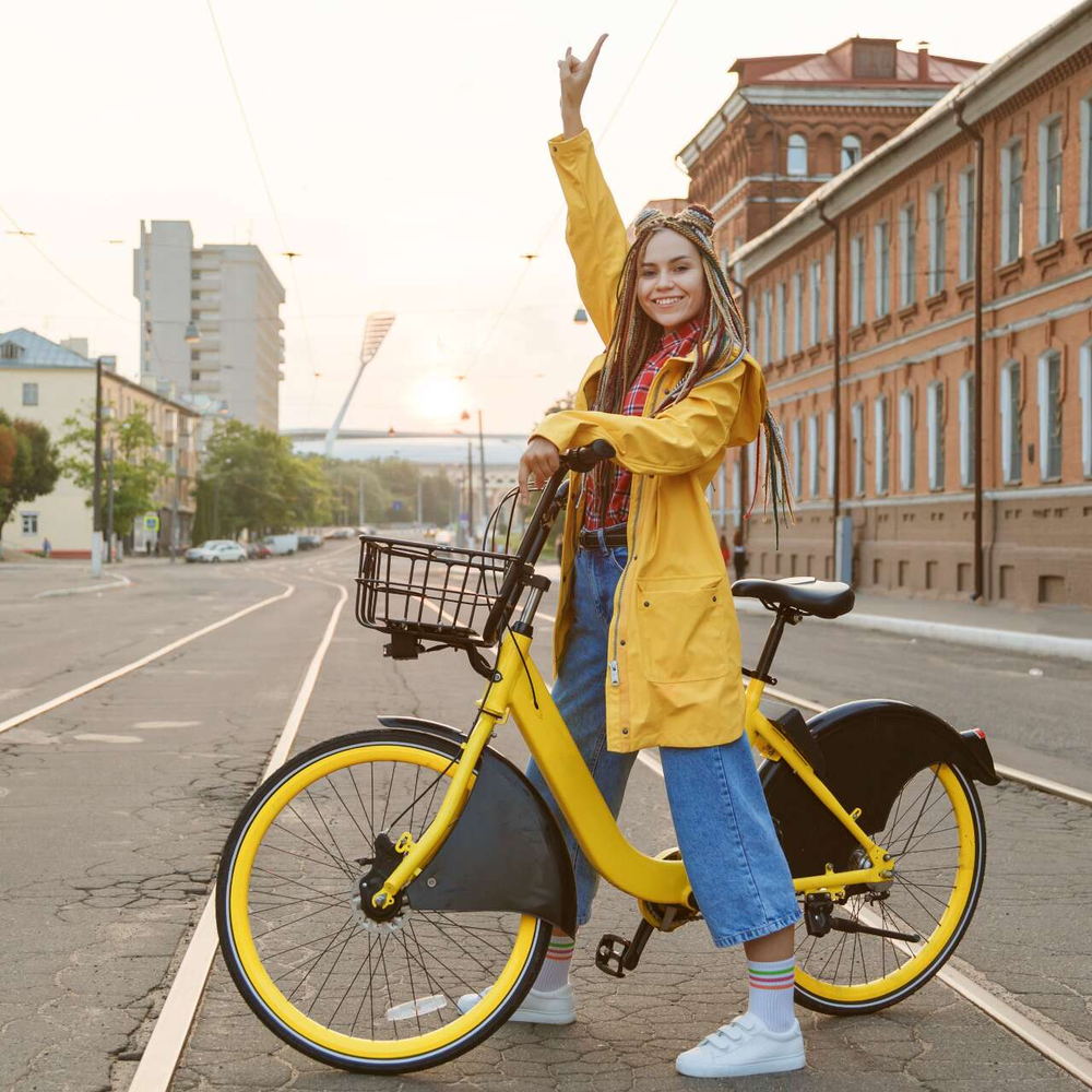 Rahmen mit bequemen Einstieg Eine Frau sitzt auf einem Fahrrad und hebt die Hand.