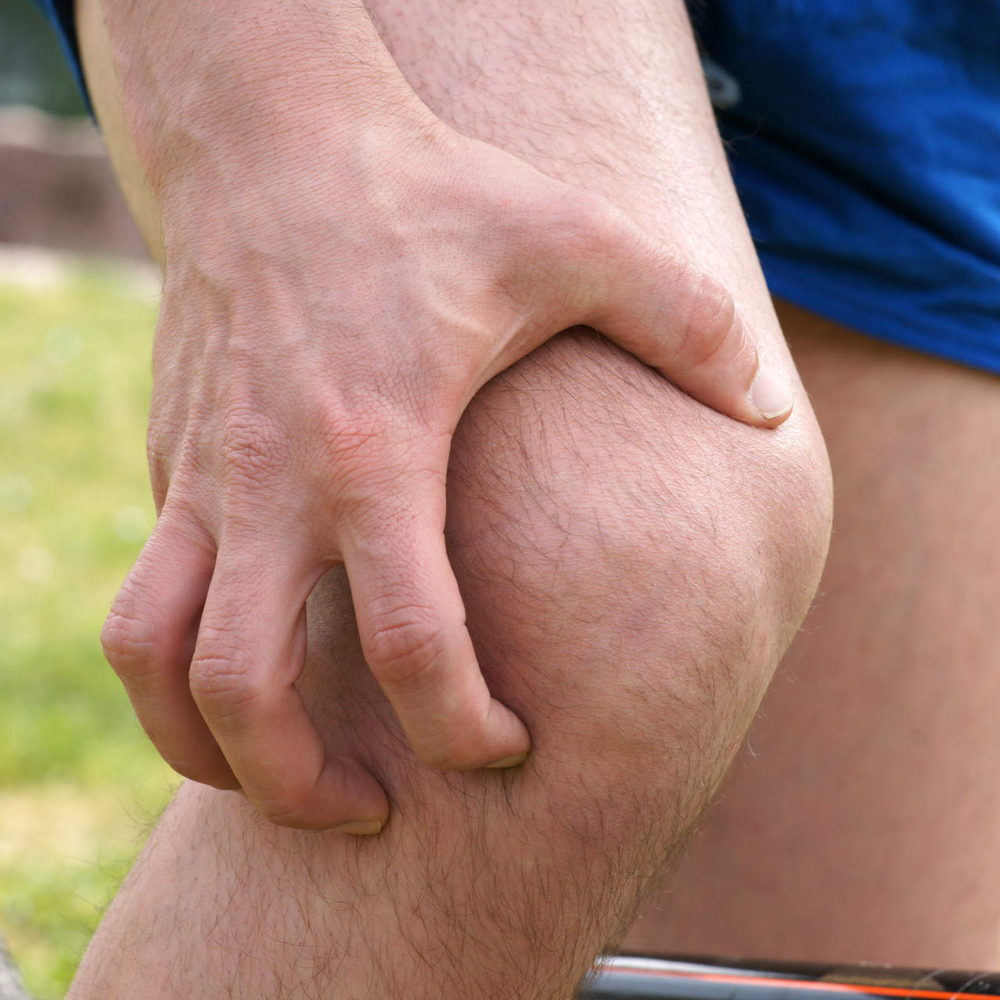 So gelingt schmerzfreies Radfahren Person hält sich das Knie beim Radfahren