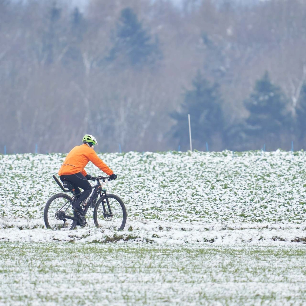 Kann bei Schnee mit dem Fahrrad gefahren werden? Fahrradfahrer fährt im Schnee
