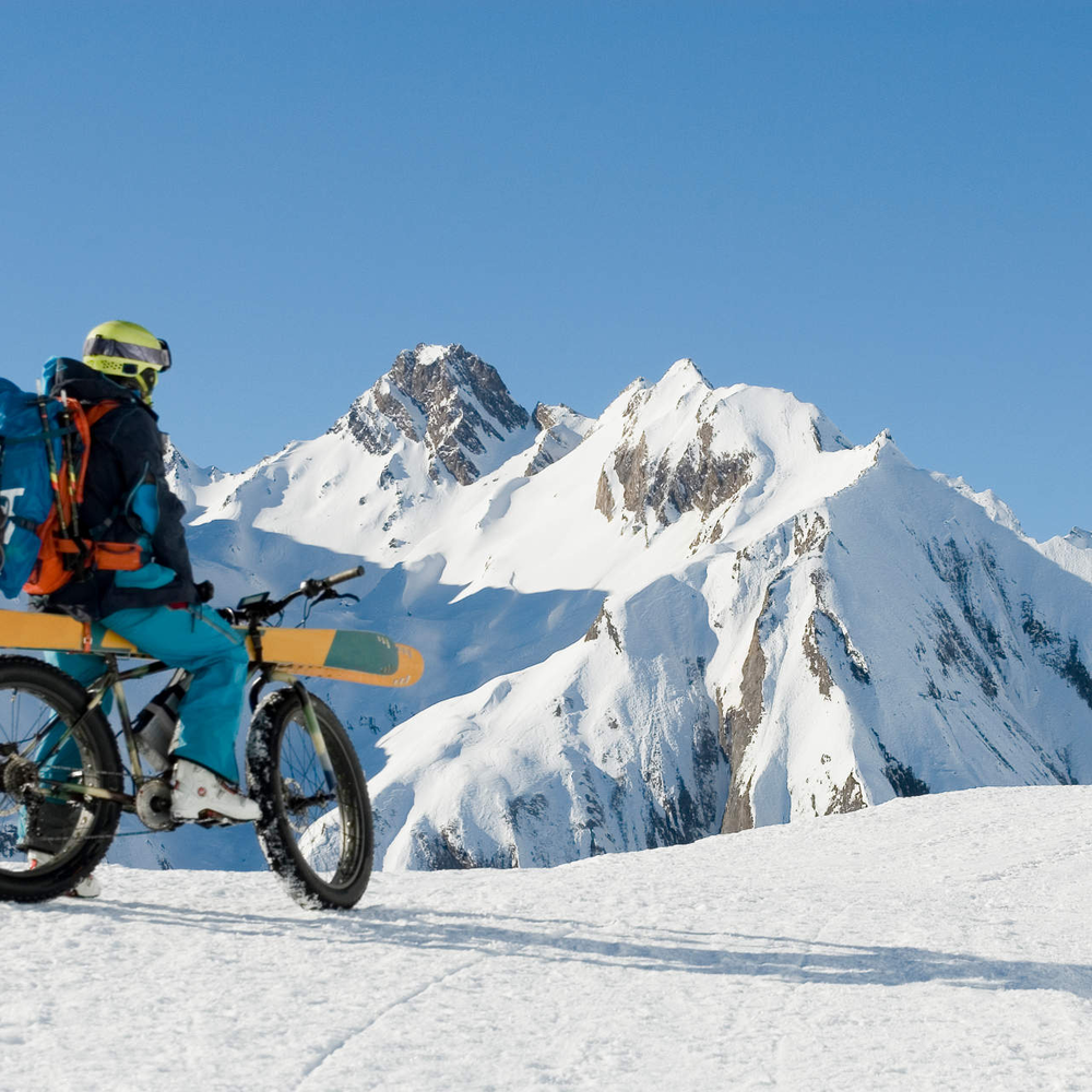 Skier fürs E-Bike - nachhaltig auf der Piste Ein E-Bike Fahrer fährt im Schnee mit seinen Skiern
