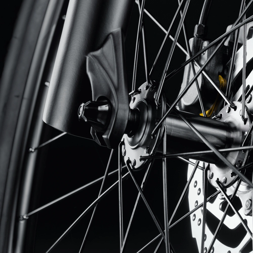 Nahaufnahme eines Fahrradbremsen mit Speichen auf schwarzem Hintergrund.