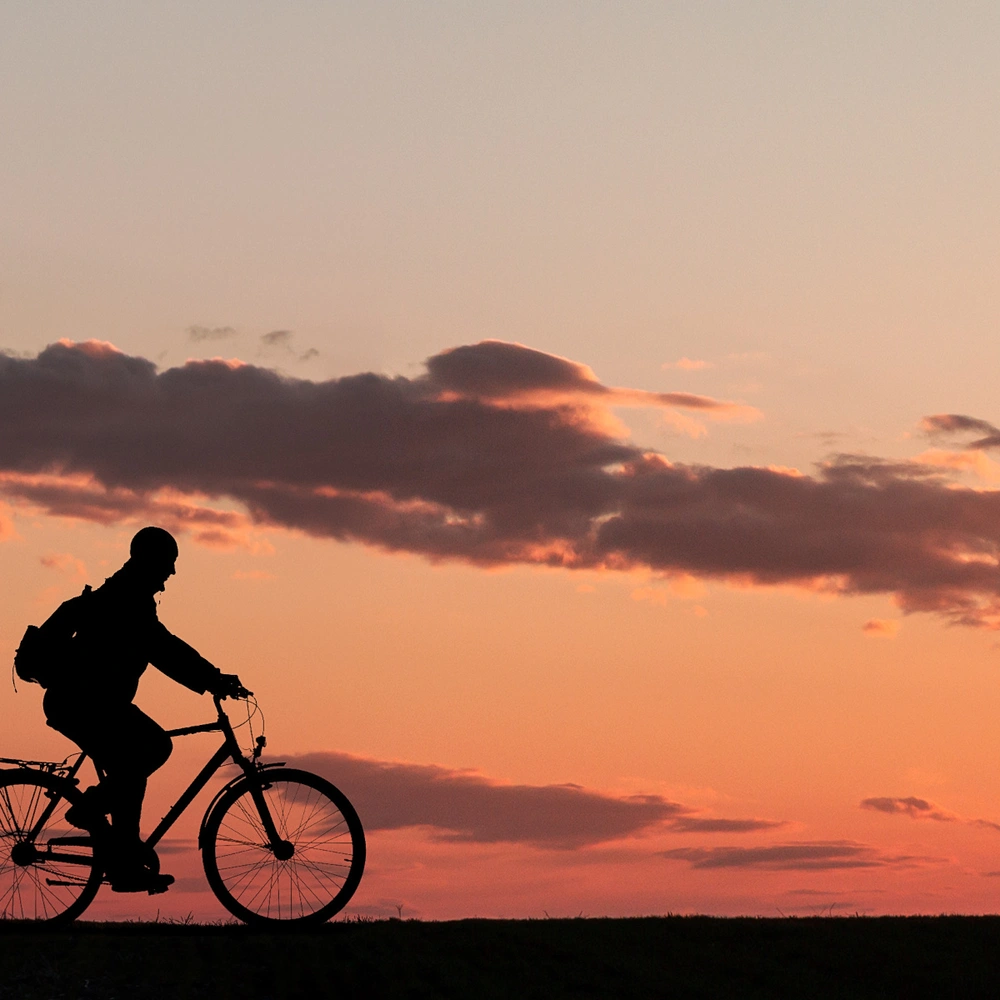 Silhouette einnes Mannes auf einem Fahrrad im Sonnenuntergang.