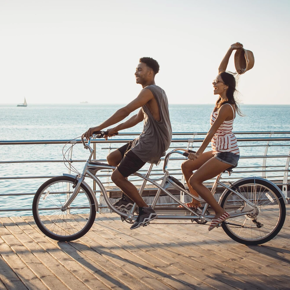 Paar fährt glücklich auf einem Tandemrad am Strand entlang