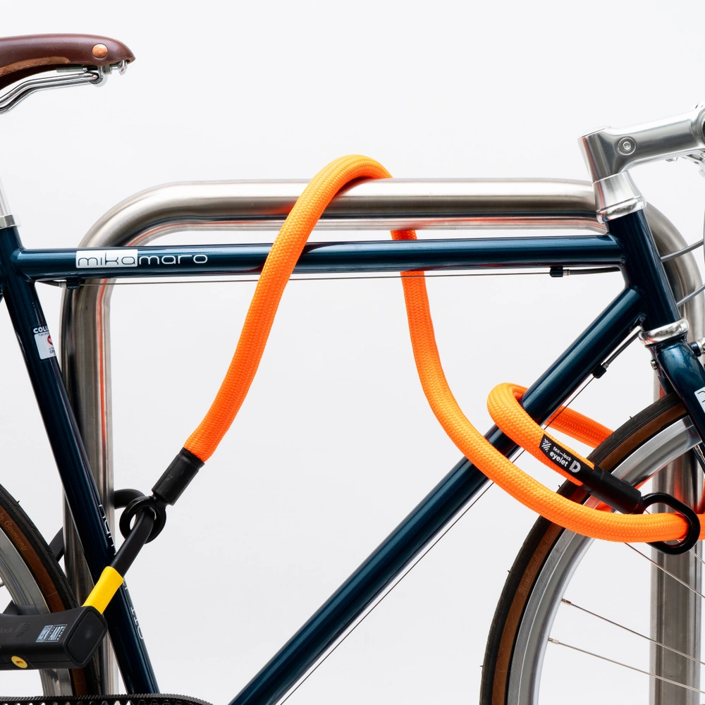 Blaues Fahrrad mit einem orangefarbenen Schloss, an einem Metallpfosten gesichert.