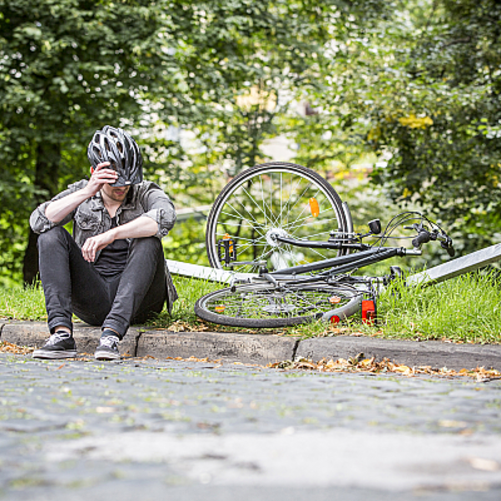 Schnell wieder mobil mit dem Aktions-Komplettschutz Bike, Bild: WERTGARANTIE | © SVEN BRAUERS Radfahrer sitzt am Wegrand nach einem Sturz mit kaputtem Fahrrad