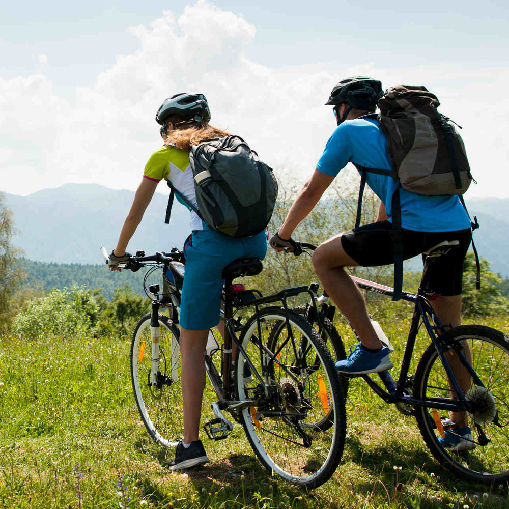 XXL Bikes für große Menschen – darauf sollten Sie achten. Mann und Frau auf Fahrrad schauen in Bergland.