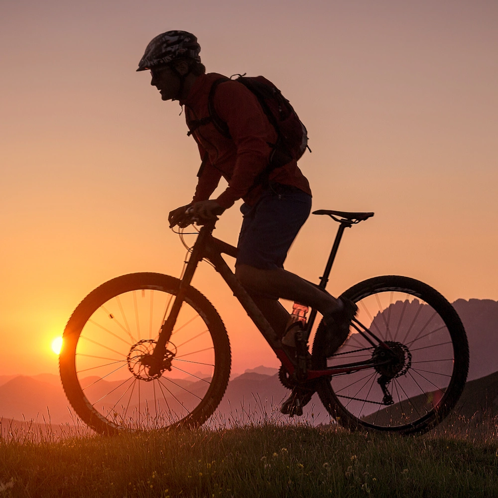 Entdecke die innovative Fahrradmarke Zündapp Mann fährt mit einem Mountainbike durch Gebirge im Sonnenuntergang