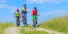 Die besten E-Bike Touren - für deinen nächsten Urlaub Drei E-Bike Fahrer, fahren auf einem Gelände