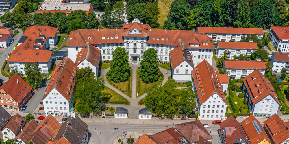 Luftaufnahme eines Gebäudekomplexes mit roten Dächern und grünen Gärten.