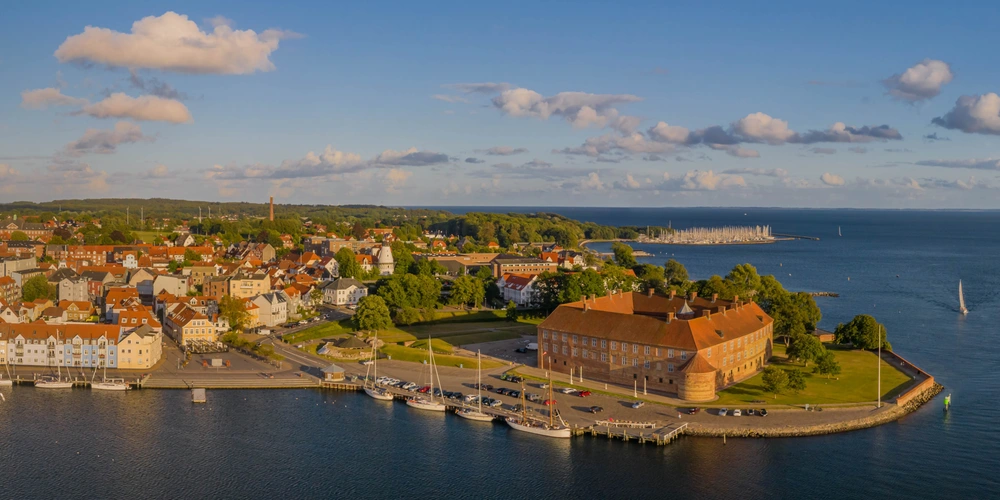 Panoramaansicht einer Küstenstadt Sonderborg mit Wasser, Häusern und einem historischen Gebäude.