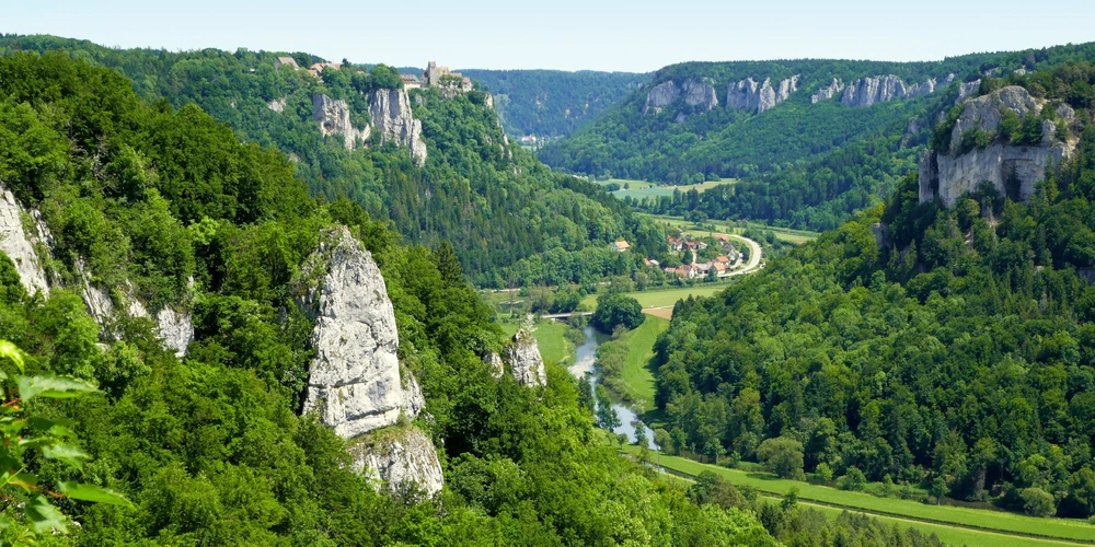 Blick auf eine grüne Schlucht mit Felsen und einem Fluss im Tal.