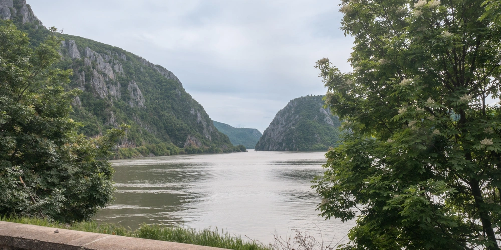 Blick auf die Donau, umgeben von steilen Bergen und bewaldeten Ufern.