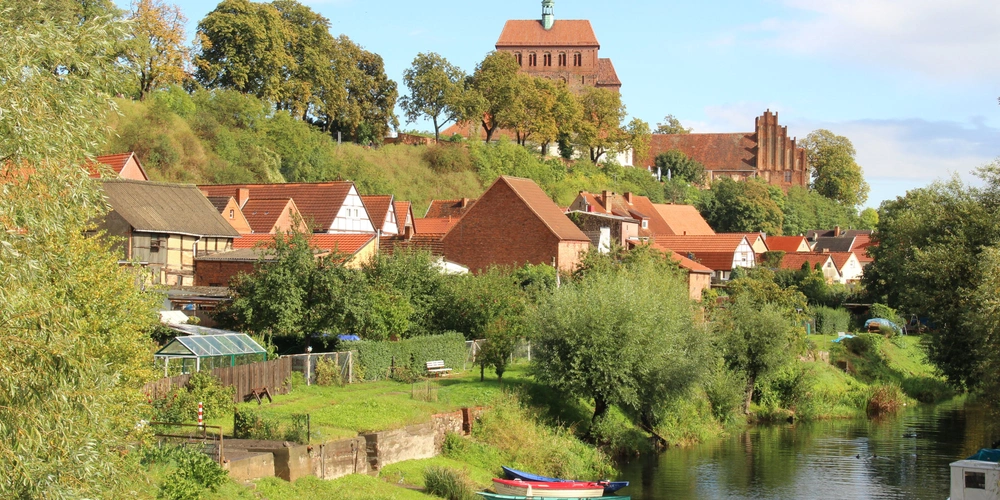 Havelberg Idyllische Uferlandschaft mit historischen Gebäuden und grünen Bäumen.