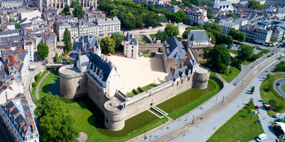 Luftaufnahme einer modernen Stadt mit einem historischen Schloss und Grünflächen.