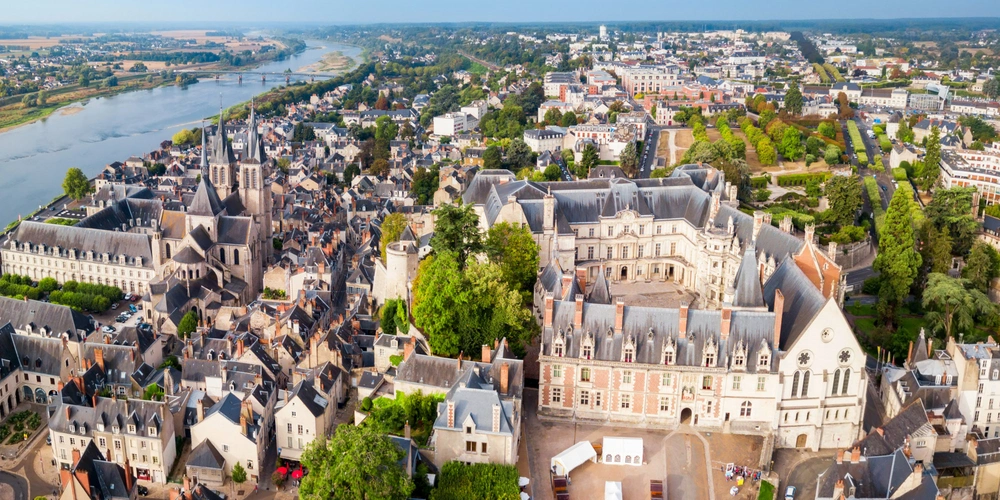 Luftaufnahme einer Stadt mit grünen Landschaften, Fluss und historischen Gebäuden.