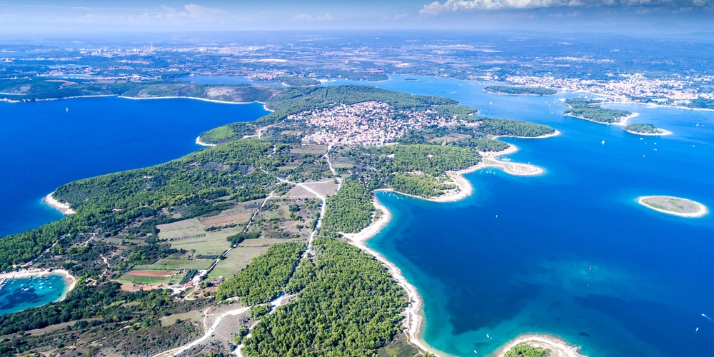 Luftaufnahme von Kamenjak mit klarem blauen Wasser und grüner Vegetation.