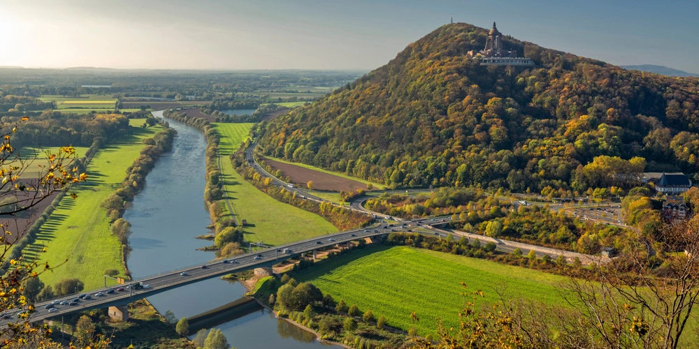 Weser mit Kaiser Wilhelm Denkmal Porta Westfalica Panoramablick auf die Weser, Hügel und herbstlich gefärbte Landschaft.