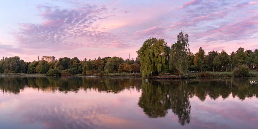 Ruhiger See bei Sonnenuntergang mit buntem Himmel und spiegelnder Wasseroberfläche.
