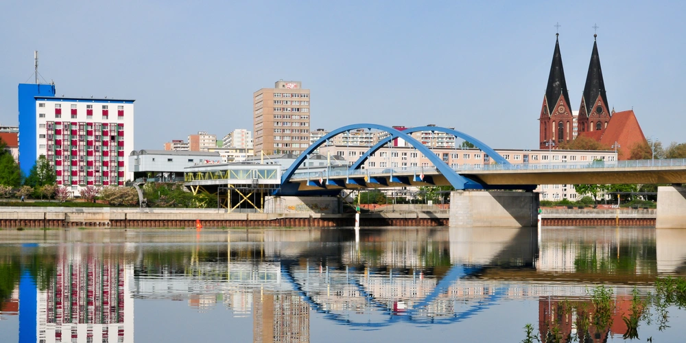 Blick auf eine Brücke über die Oder in Frankfurt (Oder) mit blauer Bogenkonstruktion und reflektierenden Wasserflächen.