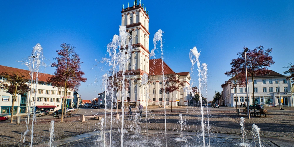 Brunnen mit Wasserfontänen vor historischem Gebäude an einem klaren Tag.