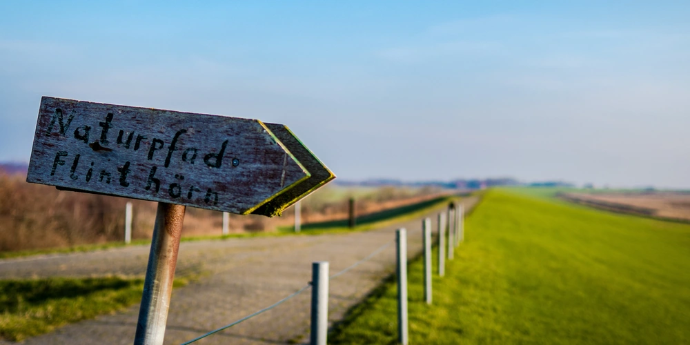 Wegweiser zum Naturpfad Flinthorn an einem ruhigen, offenen Feld.