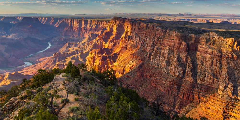 Blick auf den Grand Canyon mit dramatischen Felsformationen und fließendem Fluss.