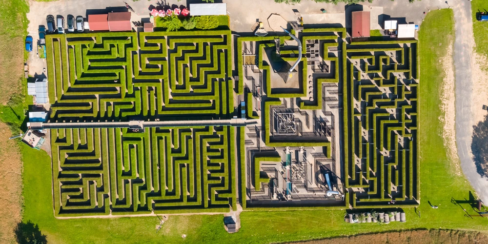 Luftaufnahme eines großen grünen Labyrinths mit verschiedenen Wegen und Umrandungen.