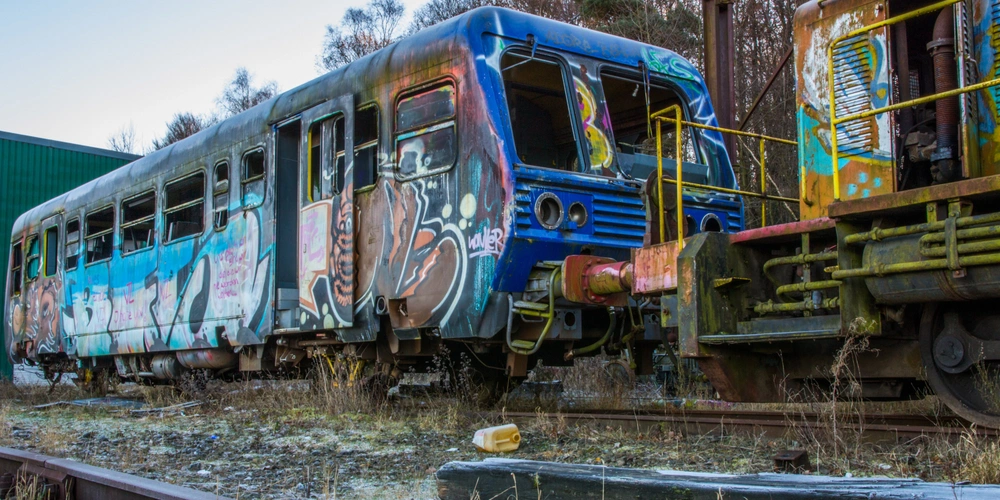 Historische Bahn am Bahnhof Raeren Graffitibedeckter Zugwagen in einer verlassenen Gleislandschaft.