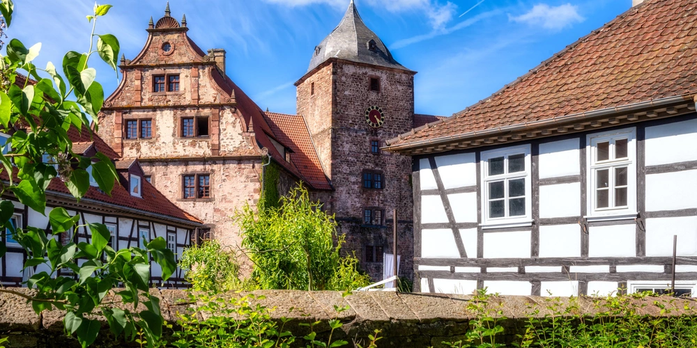 Historische Fachwerkhäuser und ein Turm unter blauem Himmel.