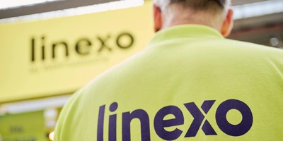 Rücken eines Vertriebsmitarbeiters mit linexo Shirt vor dem Messestand