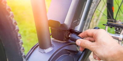 Person verbindet ein Kabel mit dem Akku 750 h eines E-Bikes, um diesen zu laden