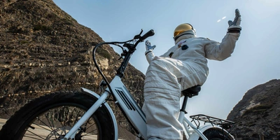 Astronaut sitzt auf einem Fahrrads mit Metallreifen