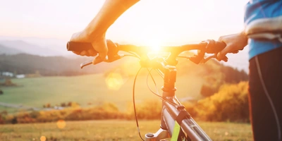 Ein Mann steht mit dem Fahrrad dem Sonnenuntergang entgegen