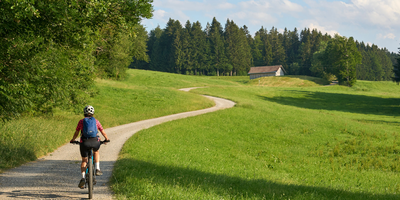 Eine Frau fährt mit einem E-Bike einen langen Weg in der Natur entlang