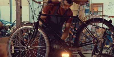 Ein junger Mann schraubt an einem Fahrrad in einer Werkstatt.