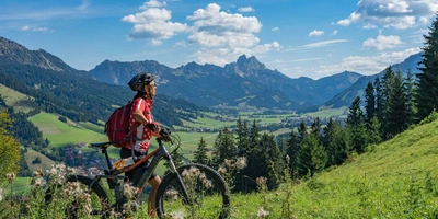 Frau schiebt E-Mountainbike durch die Berge