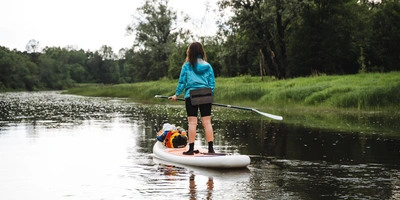 Frau fährt mit einem Stand Up Paddle auf einem Fluss