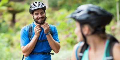 Mann setzt Fahrradhelm auf und schaut Frau an.