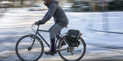 Es ist wichtig, dass die Arbeitgeber die Fahrradfahrer in Ihrem Betrieb unterstützen. Mann fährt im Winter mit Fahrrad über verschneiten Radweg